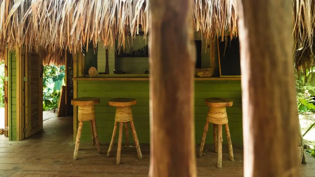 Bar rústico con techo de palma y taburetes de madera